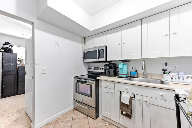 kitchen featuring stainless steel appliances, white cabinetry, sink, and light tile patterned floors