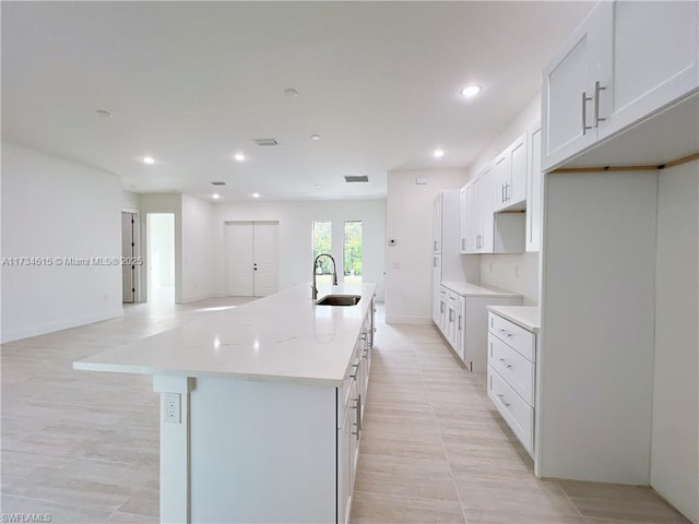 kitchen featuring white cabinetry, an island with sink, sink, and light tile patterned floors