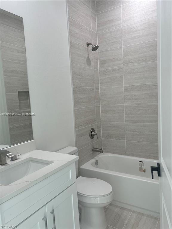 full bathroom featuring vanity, tiled shower / bath combo, and toilet