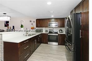 kitchen with sink, light hardwood / wood-style flooring, stainless steel appliances, and kitchen peninsula