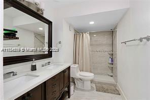 bathroom featuring toilet, vanity, and a shower with curtain