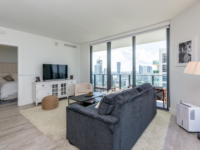 living room with floor to ceiling windows, a healthy amount of sunlight, and light hardwood / wood-style floors