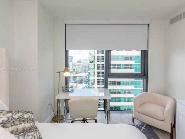 bedroom with a wall of windows and hardwood / wood-style floors