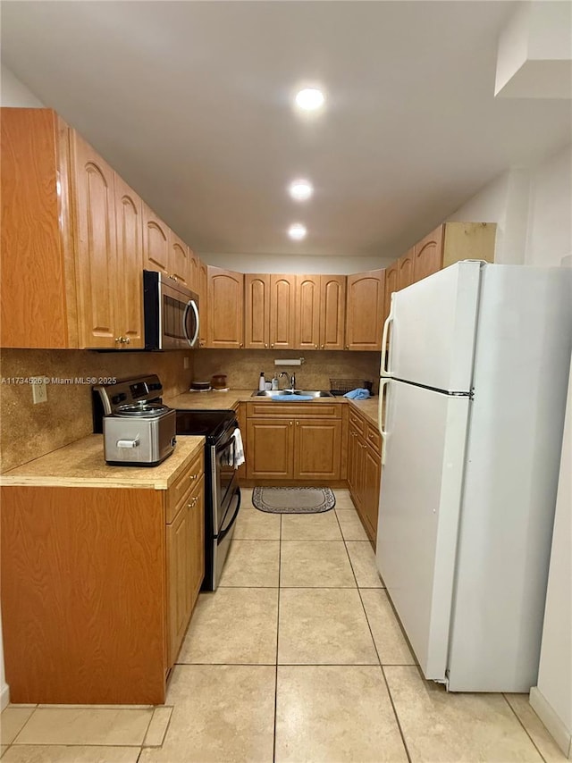 kitchen with tasteful backsplash, sink, light tile patterned floors, and stainless steel appliances