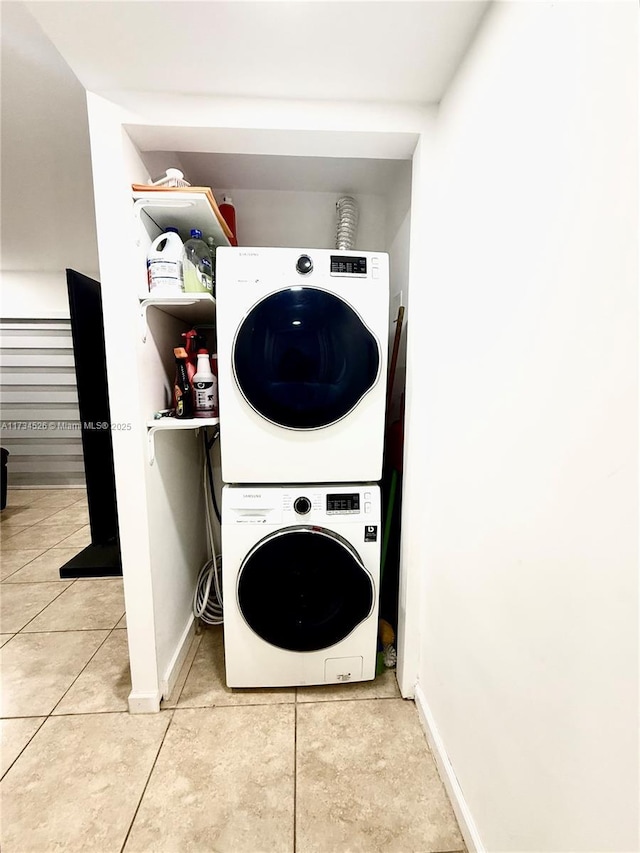 clothes washing area featuring light tile patterned flooring and stacked washer / drying machine