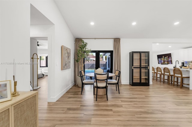 dining room with sink, light hardwood / wood-style flooring, and french doors