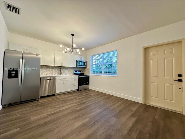 kitchen with white cabinetry, an inviting chandelier, dark hardwood / wood-style floors, stainless steel appliances, and decorative backsplash