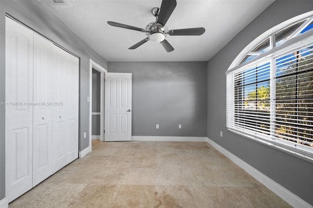 unfurnished bedroom with ceiling fan, a textured ceiling, and a closet