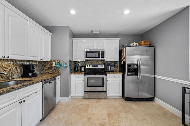 kitchen featuring sink, appliances with stainless steel finishes, dark stone countertops, tasteful backsplash, and white cabinets