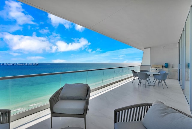 balcony featuring a water view, a view of the beach, and radiator