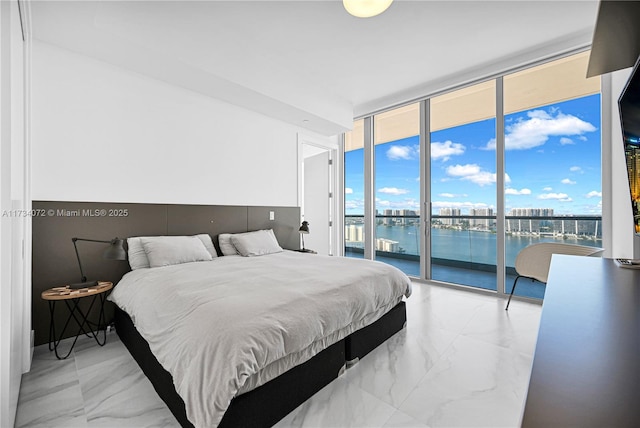 bedroom featuring multiple windows, access to outside, a wall of windows, and a water view