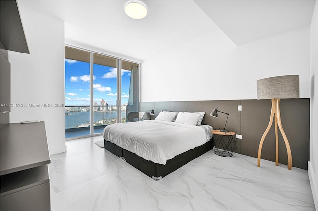 bedroom with floor to ceiling windows, a water view, and access to exterior