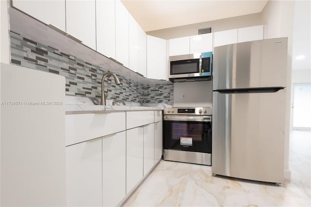 kitchen featuring tasteful backsplash, appliances with stainless steel finishes, sink, and white cabinets