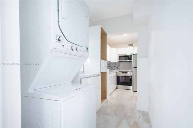 clothes washing area featuring stacked washer / dryer