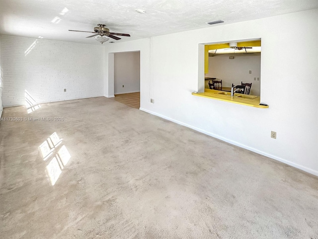 carpeted spare room featuring ceiling fan, brick wall, and a textured ceiling