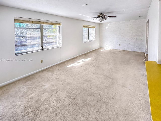 spare room with brick wall, carpet flooring, a textured ceiling, and ceiling fan