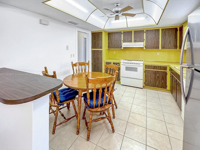 kitchen with light tile patterned floors, stainless steel fridge, white electric stove, a raised ceiling, and ceiling fan