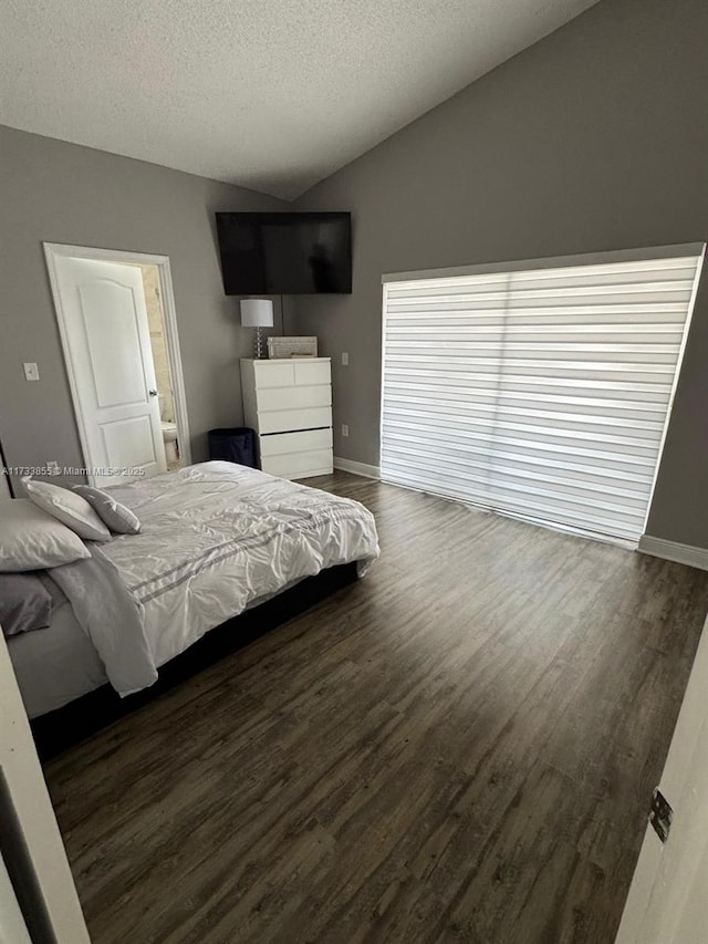 bedroom with dark hardwood / wood-style flooring, vaulted ceiling, and a textured ceiling