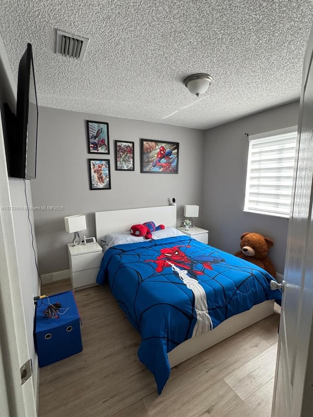 bedroom featuring hardwood / wood-style flooring and a textured ceiling