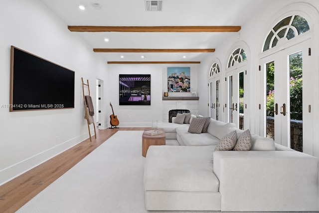 living room with french doors, beam ceiling, and light wood-type flooring