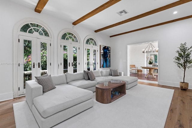 living room with light hardwood / wood-style floors, a notable chandelier, beam ceiling, and french doors