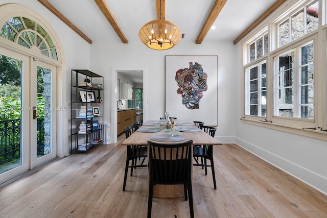 dining room with a notable chandelier, light hardwood / wood-style flooring, sink, and beamed ceiling