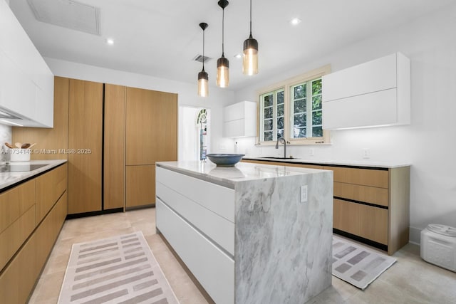 kitchen featuring white cabinetry, sink, pendant lighting, and a kitchen island