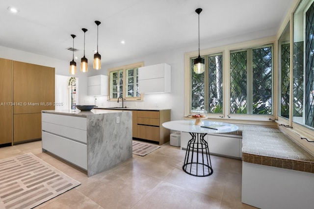 kitchen with sink, white cabinets, hanging light fixtures, a center island, and plenty of natural light