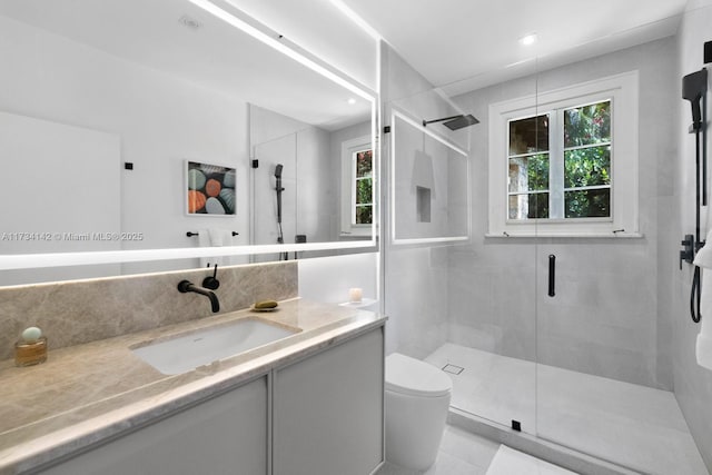 bathroom with vanity, plenty of natural light, a shower with door, and toilet