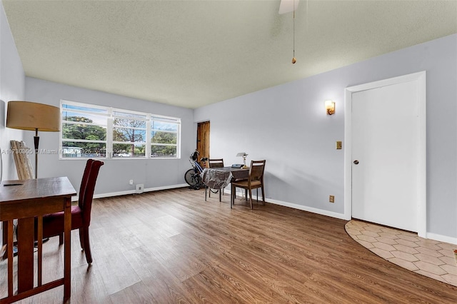 dining room with wood-type flooring and a textured ceiling