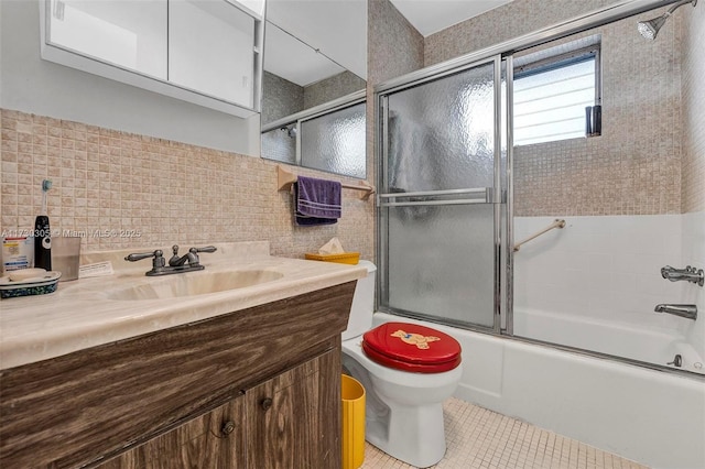 full bathroom with tile walls, tile patterned flooring, enclosed tub / shower combo, vanity, and toilet