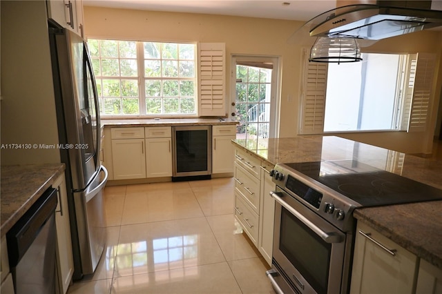 kitchen with wine cooler, stainless steel appliances, dark stone counters, and light tile patterned flooring