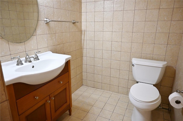 bathroom featuring vanity, tile patterned flooring, toilet, and tile walls