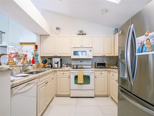 kitchen featuring white appliances, lofted ceiling, sink, and backsplash