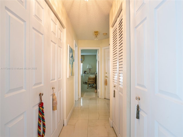 hall with light tile patterned flooring and a textured ceiling