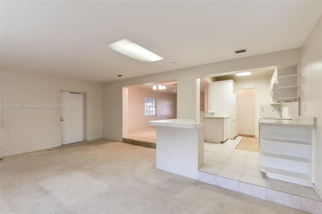 kitchen with white refrigerator, sink, light carpet, and kitchen peninsula