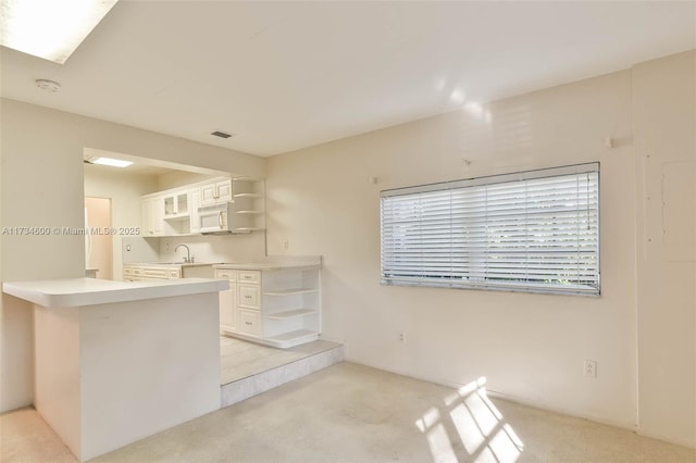 kitchen featuring white cabinetry, light colored carpet, and kitchen peninsula