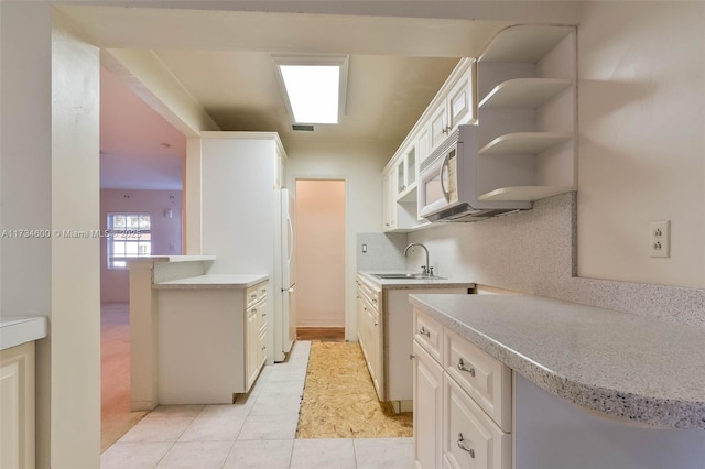 kitchen with sink, light tile patterned floors, kitchen peninsula, white appliances, and decorative backsplash