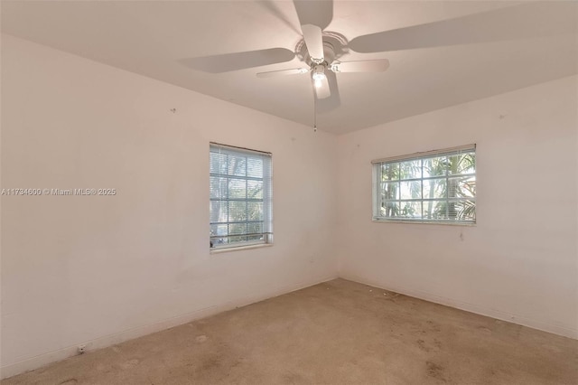 spare room with ceiling fan, light colored carpet, and a wealth of natural light