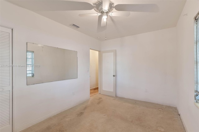 empty room with ceiling fan and light colored carpet