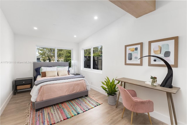 bedroom with vaulted ceiling and light wood-type flooring