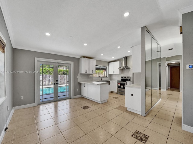 kitchen with sink, wall chimney range hood, electric range, white cabinets, and french doors