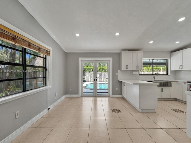 kitchen with white cabinetry, sink, decorative backsplash, and french doors