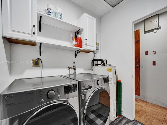 laundry room featuring cabinets, wood-type flooring, electric water heater, and washer and clothes dryer