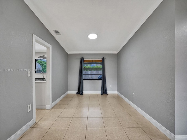 empty room with light tile patterned flooring, crown molding, and sink