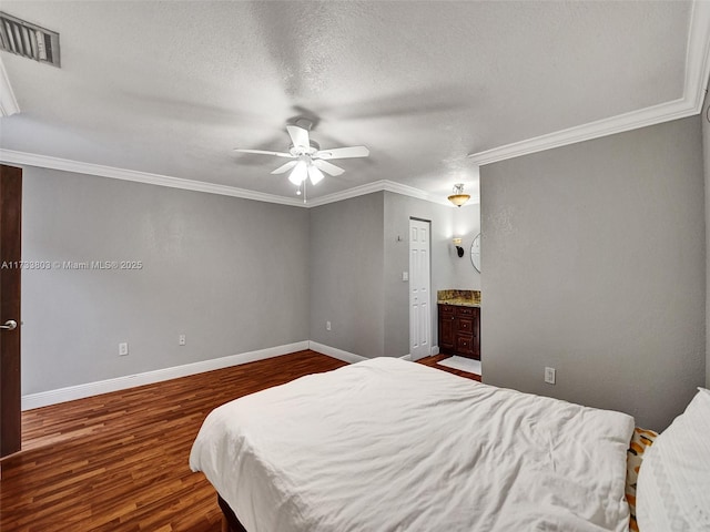 bedroom with crown molding, dark wood-type flooring, ensuite bath, ceiling fan, and a textured ceiling