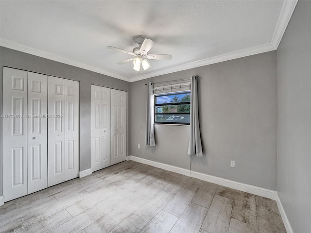 unfurnished bedroom with light hardwood / wood-style flooring, a textured ceiling, multiple closets, ornamental molding, and ceiling fan