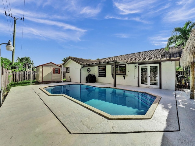 view of swimming pool with french doors, a patio area, and a shed