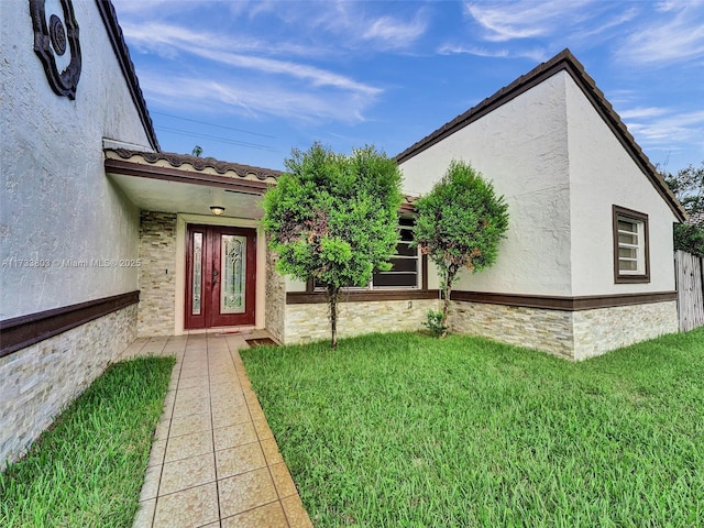 view of exterior entry featuring a lawn