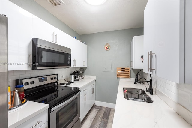 kitchen featuring white cabinetry, sink, backsplash, and appliances with stainless steel finishes